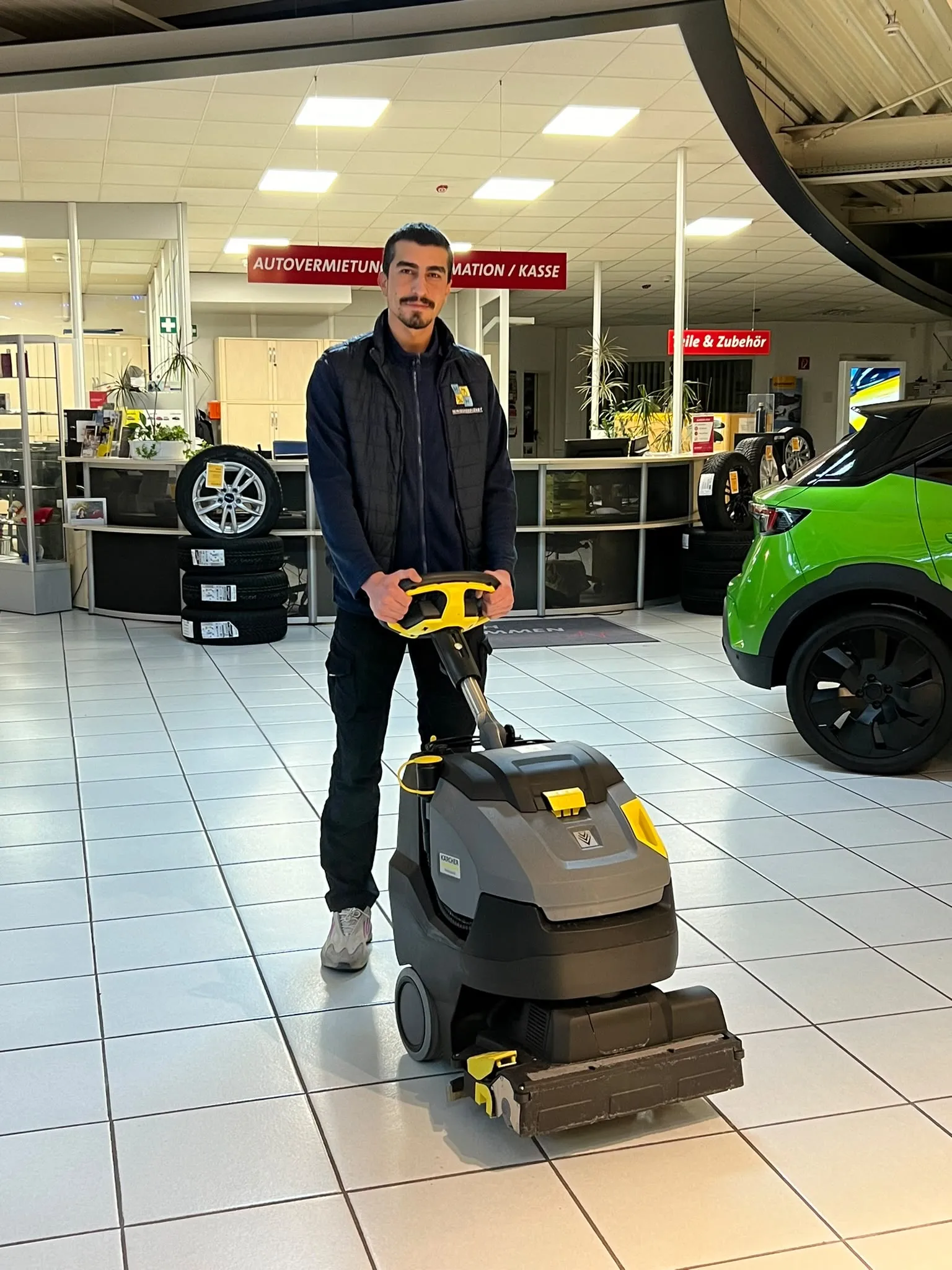 Mitarbeiter von MH Reinigungsdienst mit einer Scheuersaugmaschine in einem Autohaus